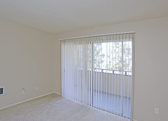 Carpeted master bedroom with sliding glass door to private porch at Villa Pacific Apartments in Oceanside, California.