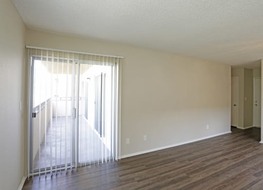 Living room with plank style flooring and sliding glass doors to private porch at Villa Pacific Apartments in Oceanside, California.