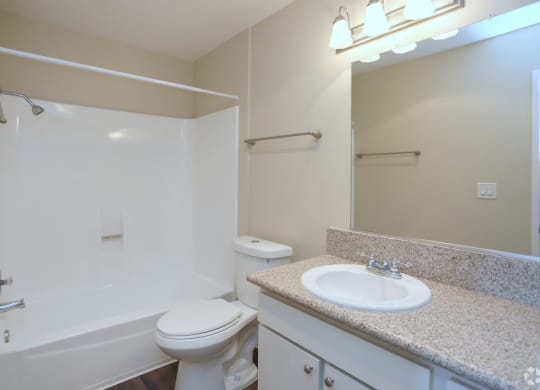 Bathroom with white fixtures and vanity with white cabinets in unit at Villa Pacific Apartments in Oceanside, California.