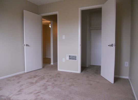 Carpeted bedroom with walk-in closet at Villa Pacific Apartments in Oceanside, California.