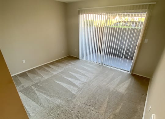 Carpeted bedroom with sliding glass door access to private porch at Villa Pacific Apartments in Oceanside, California.