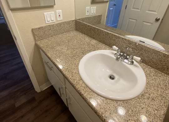 Bathroom with plank style flooring and vanity with white cabinets at Villa Pacific Apartments in Oceanside, California.