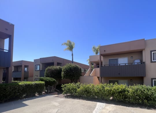 Private patios and balconies amongst manicured bushes and trees at Villa Pacific Apartments in Oceanside, California.