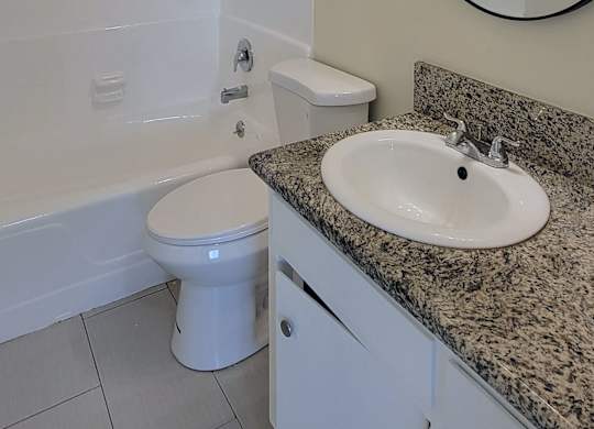 A bathroom with a sink, toilet, and a mirror.