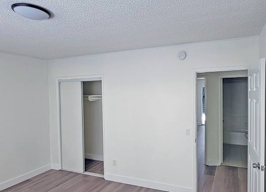 A room with a white ceiling and a doorway leading to another room.