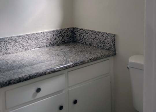 A white toilet sits next to a window in a bathroom.
