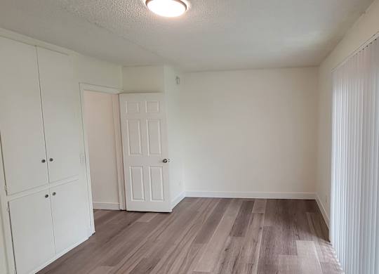 A room with white cupboards and a wooden floor.