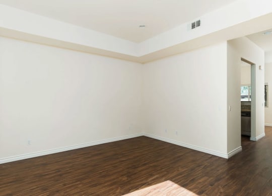 Living room with wood style laminate flooring, windows and access to private porch at The Nines Townhomes in Escondido, California.