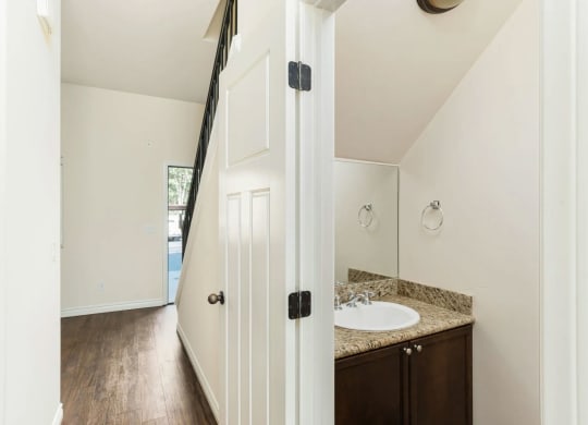 Half bathroom downstairs with dark wood vanity and granite slab top and upgraded fixtures in apartment at The Nines Townhomes in Escondido, California.