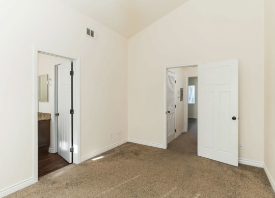 Carpeted bedroom with cathedral ceinling and bathroom at The Nines Townhomes in Escondido, California.