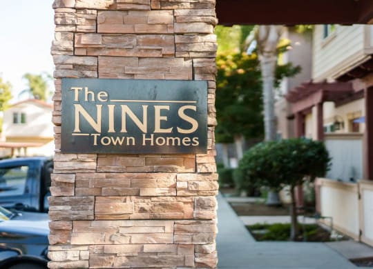 Stone column with The Niines Town Homes sign near front enterance in Escondido, California.