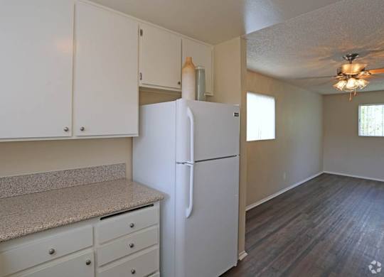 A white refrigerator in a kitchen with white cabinets and a counter.