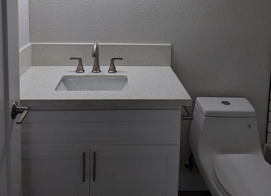 Lots of bathroom lighting and white fixtures at The Hardison Apartments in Pasadena, California.