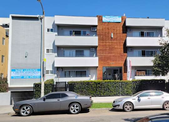Two cars are parked in front of a multi-story building.