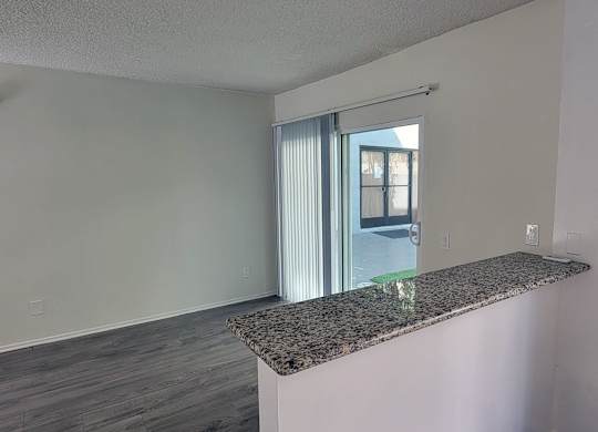 A room with a granite countertop and a sliding glass door.