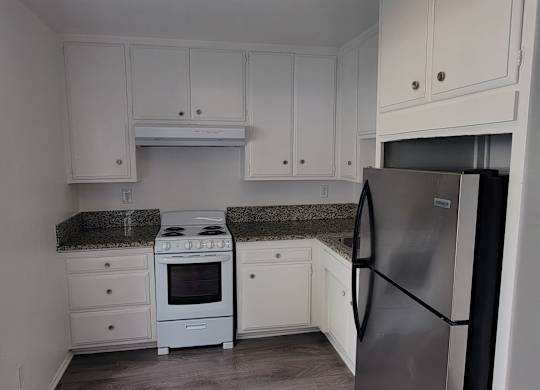 A kitchen with white cabinets and a black fridge.