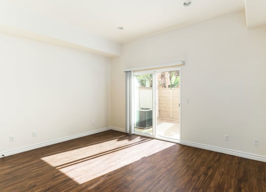 Living room with wood style laminate floors and sliding glass doors to private porch at The Nines Townhomes in Escondido, California.