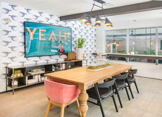 a dining area with a wooden table and chairs and a large flat screen tv on the wall