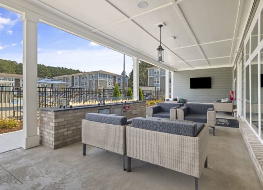 a covered patio with couches and chairs and a wall of windows