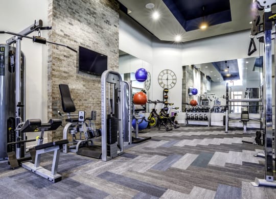 a spacious fitness center with cardio equipment and a large clock on the wall