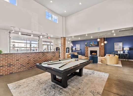 A pool table is in the middle of a room with a brick wall.