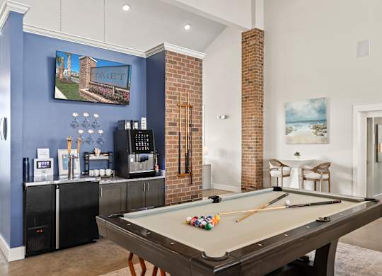 A pool table in a room with a blue wall and a fridge.