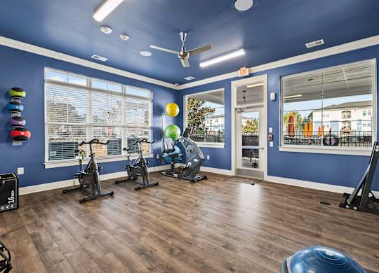 A gym with exercise equipment and a window overlooking a residential area.
