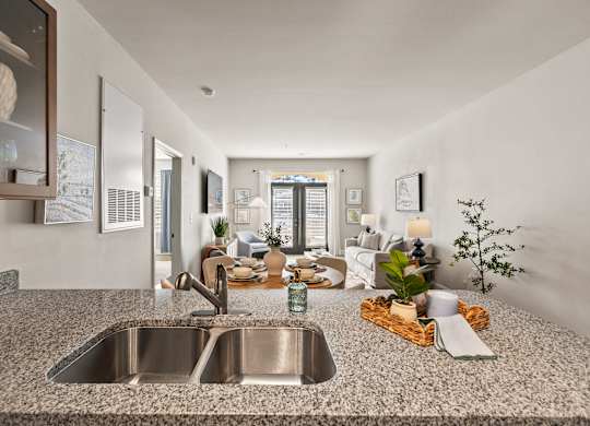 A modern kitchen with a granite countertop and a stainless steel sink.