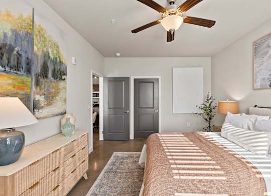 A bedroom with a bed, dresser, and painting on the wall.