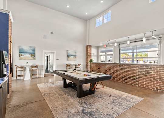 A room with a pool table and a brick wall.