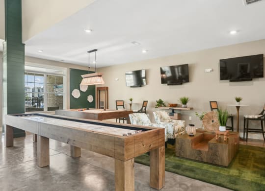 a living area in the clubhouse with shuffleboard and a television