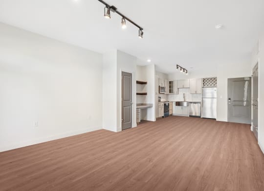 an empty living room and kitchen with a wood floor