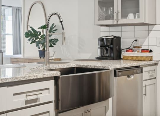 a kitchen with white cabinets and a stainless steel sink