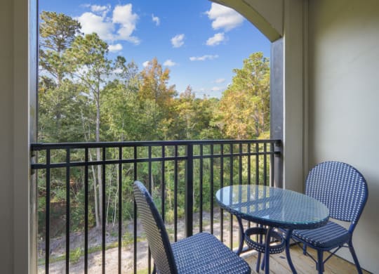 a balcony with a table and chairs and a view of trees