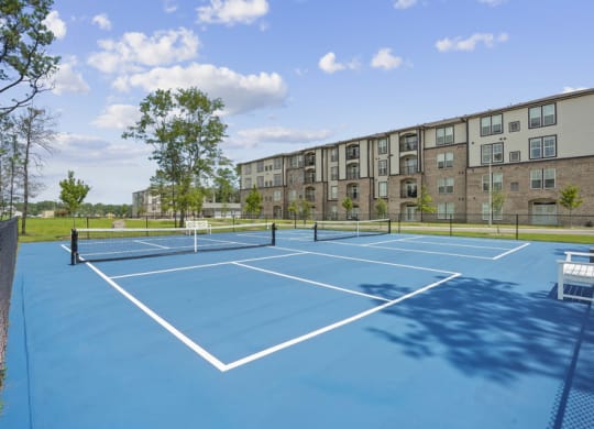a picleball court with an apartment building in the background