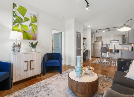 a living room with furniture and a kitchen in the background