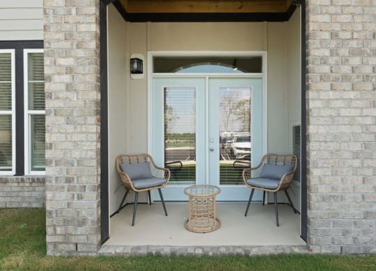 the front porch of a house with two chairs and a table