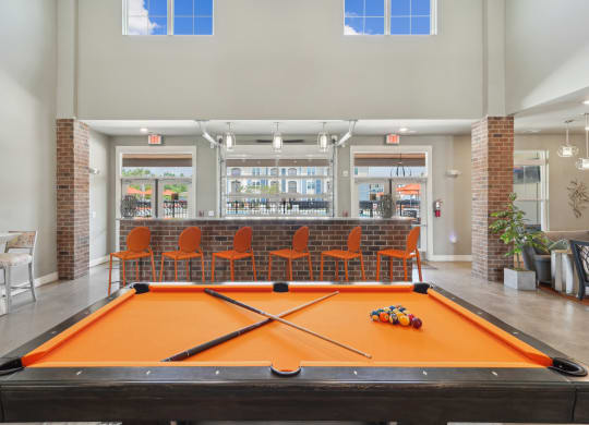 a pool table in a clubhouse with a bar in the background