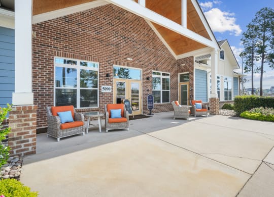 a patio with chairs in front of a brick building