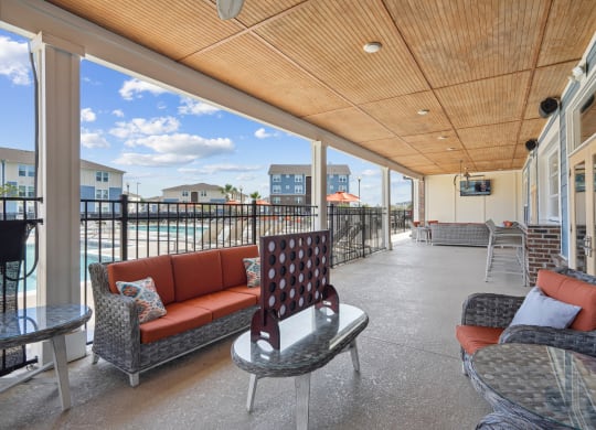 a covered porch with couches and chairs and a view of the ocean