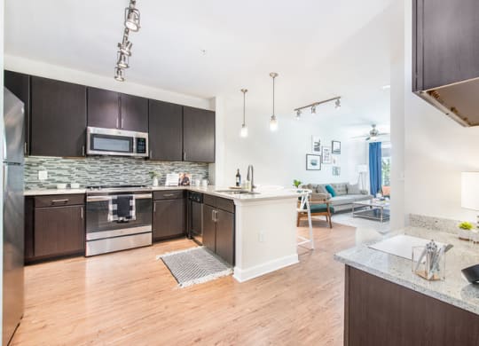 a kitchen and living room with wood flooring and stainless steel appliances