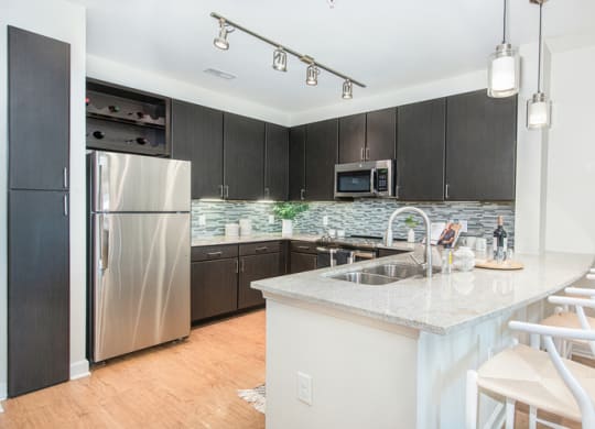 a kitchen with a large island and a stainless steel refrigerator