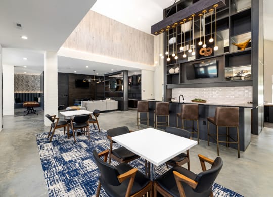 a communal area with tables and chairs and a kitchen and living room