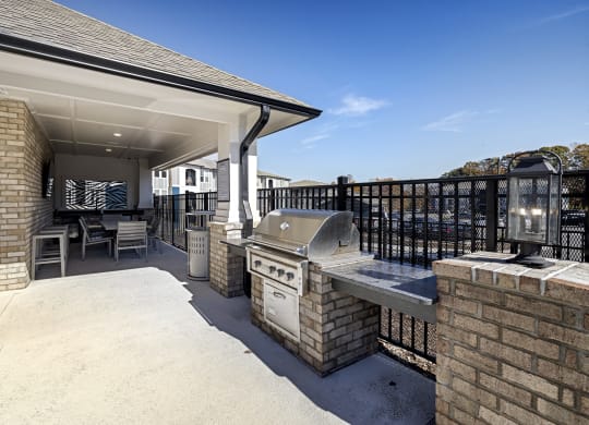 a covered patio with a barbecue grill and a table and chairs