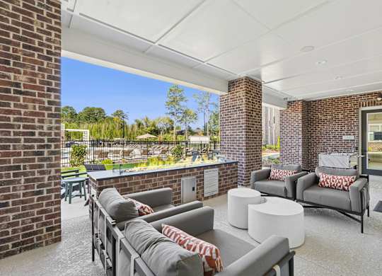 A patio with a white couch and a grey couch with a red and white throw on it.