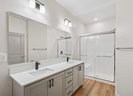 A bathroom with a sink, mirror, and shower.