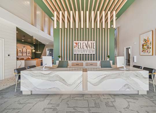 A reception area with a white reception desk and a green wall with a sign that says