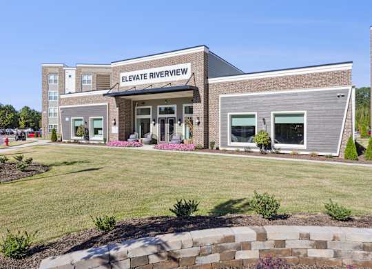 The front of the Elevate Riverview building is shown with a clear blue sky in the background.