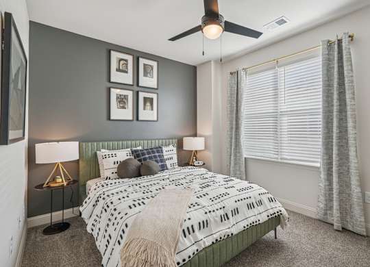 A bedroom with a bed, two lamps, and a ceiling fan.