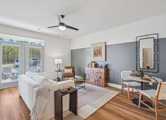 A living room with a white couch, a wooden coffee table, and a dining table set up.